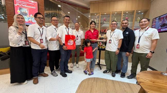 Saki H Bramono, Vice President Consumer Business Sumatera (tiga dari kanan) menyerahkan potongan tumpeng kepada salah seorang pelanggan.