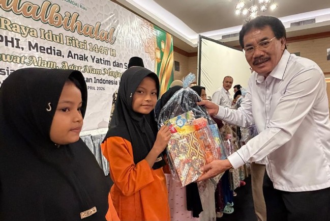 Ketua APHI Riau, Muller Tampubolon, SE, MM menyerahkan bibgkisan kepada anak yatim panti asuhan.