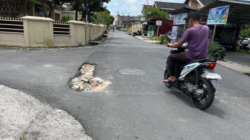 Seorang pengendara melintasi satu ruas jalan amblas di sekitar Jalan Dagang, Kota Pekanbaru. (Foto: Tribun Pekanbaru)