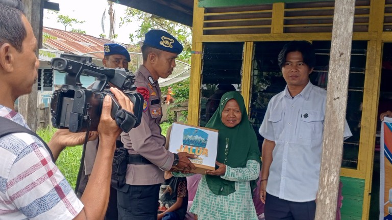 Kanit Patroli Satpol Airud Polres Rohil, Bripka Mesdianto menyalurkan bantuan ke masyarakat kurang mampu di Jalan Pelabuhan Baru (foto/afrizal)