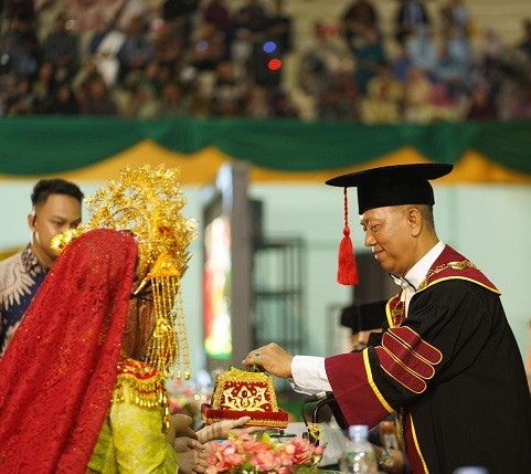 Rektor Universitas Islam Riau, Prof. Dr. Rer. Pol. H. Syafrinaldi, S.H., MCL., menerima tapur sirih sebagai simbol penghormatan dalam prosesi Wisuda Periode II Tahun 2025 di Gedung Gelora UIR, Rabu (18/6/2025).