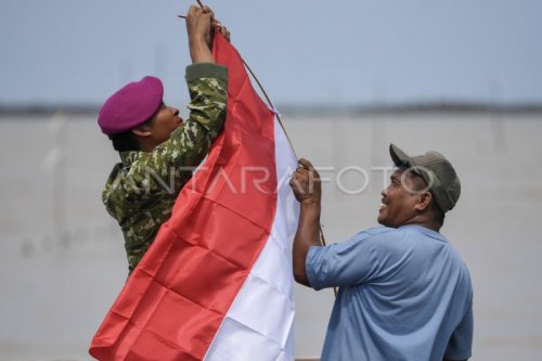 Prajurit Korps Marinir TNI AL membantu warga memasang Bendera Merah Putih yang dibagikan secara gratis di pesisir Pulau Sebatik.