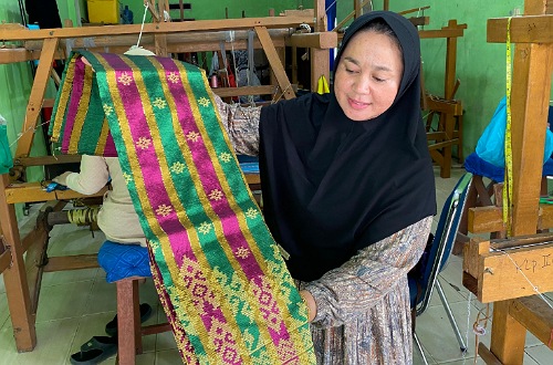 Yulhendra memperlihatkan kain tenun dari Rumah Tenun Pulau Payung Pelalawan.(foto: istimewa)