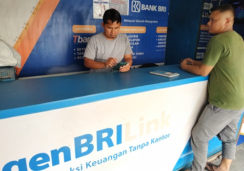 Sukarman pemilik BRIlink Abbasy Store saat melayani nasabah (foto/riki)