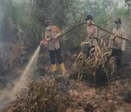 Personel Polres Dumai melakukan pemadaman karhutla.(foto: tribunpekanbaru.com)