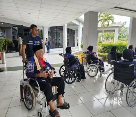 PPIH Batam membantu seorang jemaah haji Lansia asal Dumai menaiki mobil menggunakan kursi roda (foto/bambang)