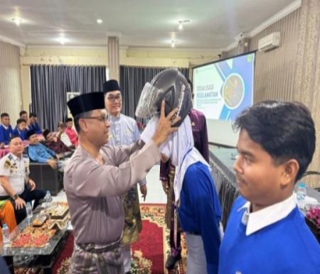 Sekda Rohil, Fauzi Efrizal pasangkan helm ke peserta sosialisasi pelajar pelopor keselamatan (foto/afrizal)