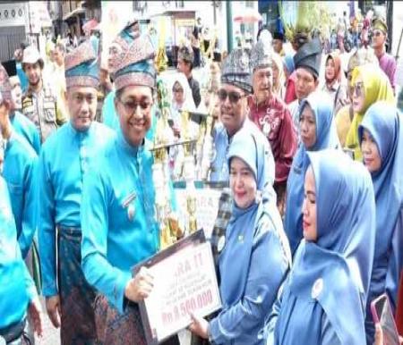 Wabup Rohil, Jony Charles menyerahkan menyerahkan hadiah kepada Kepsek SDN 007 Bagan Jawa, Jumiati yang mendapatkan Juara II dalam Festival Drumband. (Foto: Afrizal)